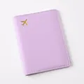 Close-up detail of the pastel purple PU leather passport cover with gold foil airplane. - Passport Cover / Purple