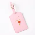 Pink leather luggage tag detail with gold letter T, hot air balloon graphic, and adjustable strap. - Letter T / Pink