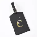 Close-up detail view of black leather luggage tag featuring gold letter C design and buckle strap. - Letter C / Black
