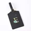 Detailed view of a black leather luggage tag featuring a gold letter E and travel motif. - Letter E / Black