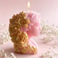 Detail shot of a pink goddess bust scented candle with gold floral relief, glowing wick. - Painted Meditating Girl / Pink
