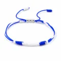 Detailed view of handmade blue and white braided friendship bracelet with metal beads - Israel