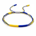 Detail view of handmade yellow and blue braided bracelet with three silver copper beads. - Sweden