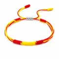 Close-up of handmade red and yellow woven friendship bracelet with three silver beads. - Spain Style