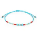 Dettaglio di un braccialetto intrecciato blu con perline rosse e blu e oro lucido - Verde