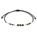 Dettaglio di un bracciale intrecciato a mano con perline nere, bianche e oro - Nero