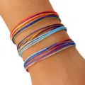 Primer plano de tres pulseras de cordón de cera trenzado impermeable de colores en la muñeca. - Estilo Naranja Verde Azul (5) / Set de tres piezas