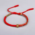 Bracelet tibétain fait main en fil rouge avec perle en cuivre gravée du mantra à six mots - Rouge
