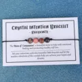 Handgemachtes Rhodonit Kristall Armband auf dekorativer weißer Displaykarte präsentiert - Rhodonit (3398) / Rosa und Schwarze Textur