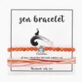 Detail view of a Zen bracelet with carnelian beads and handmade woven strings on display card. - Red Agate