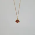 Gros plan du pendentif en grenat rouge carré sur une chaîne fine plaquée or 18 carats - Janvier