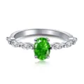 Vista detallada de anillo de plata con gema verde óvalo y acentos tipo marquise. - Estilo de Piedra Lateral Marquesa Ovalada