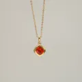 Detailed macro view of an 18K gold-plated necklace featuring a radiant orange zircon - July
