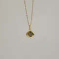 Macro view of a gold-plated necklace with an olive green square zircon pendant - August