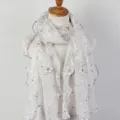 Detailed view of the elegant floral printed scarf with ruffled edges and soft lace texture. - White