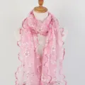 Detail view of a pink floral printed scarf with ruffled wood ear edges on a mannequin. - Pink