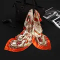 Close-up detail view of luxury 90cm satin silk square scarf with vintage horse carriage print - Orange Carriage