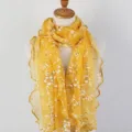Detailed view showing the yellow floral print lace scarf with delicate ruffled wood ear edges - Yellow