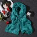Detail view of a teal linen-cotton scarf with pearl luster on a textured background. - 180x80cm / Light Blue