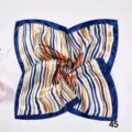 Close-up of a multi-colored striped silk square scarf with a blue border in a swirl - Blue Gold Multi Vertical Stripe (Style 10)