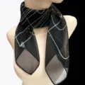 Detail view of sheer black square scarf with white grid pattern on a mannequin - Black Geometric Lines