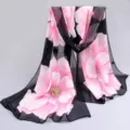Detailed view of lightweight chiffon floral scarf with elegant pink blossoms on black background - Black