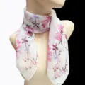 Detailansicht eines eleganten weißen Seidenschals mit rosa Blumenmuster auf einer Schaufensterpuppe - Rosa und lila Blumen auf weißem Hintergrund