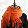 Detailed macro view of vibrant orange winter scarf with elegant fringed ends on black mannequin - 200*70cm / Orange