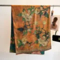 Detail view of a retro floral silk scarf draped on a rack with elegant prop accessories - 180cm / Orange Yellow And Dark Green Floral (13)