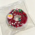 Festive Christmas themed donut squishy toy with red glaze and holiday sprinkles in a bag - Donut / Christmas Donut