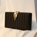 Elegante schwarze Abendtasche mit Struktur und einem edlen goldenen Blattverschluss - Schwarz