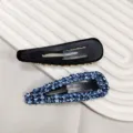 Détail macro de pinces clic-clac gouttes en strass bleu avec support en métal noir - Barrette BB Goutte d'Eau en Strass 3D / Bleu ciel