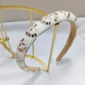 Detalle de una elegante diadema con perlas blancas y cristales dorados sobre un soporte - Diadema Perlas Cristal 1.8cm (Marrón Té)