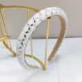 Nahaufnahme von weißen Perlen und glitzernden Strasssteinen auf einem Stirnband für Damen. - Weiß