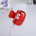 Close-up of a red cartoon toothbrush head cover with funny eyes for travel protection - Red