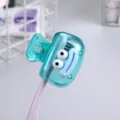 Close-up of a cute turquoise toothbrush clip with a cartoon face design - Cyan