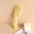 Detailed close-up view of a yellow hollowed-out hairbrush for scalp massage and hair styling - Yellow