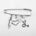 Detailed view of silver medical brooch with syringe, nurse hat, and stethoscope charms - Retro Silver (Syringe/Stethoscope/Nurse Hat/Heart)