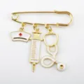 Detailed close-up of a gold-toned medical brooch with syringe and nurse hat charms - Gold Enameled Style (D-1033) / Bright Gold (Nurse Hat/Syringe/Stethoscope)