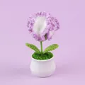 Handgemaakte paarse en witte gehaakte bloempotplant op een lichtpaarse achtergrond - Gradiënt Paars