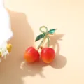 Élégante broche cerise avec feuilles en cristal vert sur fond chaleureux - Style Exquis Double Fruit Rouge Vif avec Feuille Verte (D-1759-1)