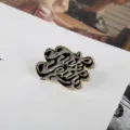 Close-up of punk enamel pin with Fuck Yeah text in gold and black finish - Gold