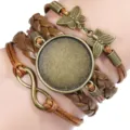 Detail of hand-woven bracelet with bronze butterfly and infinity charms on a wrist - Brown