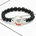 Close-up detail of a stretch bracelet featuring a glass gem with floral art and quote - 12032514