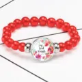 Close-up of red beaded bracelet featuring a Joy of the Lord glass charm and floral art - 12032516