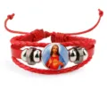 Close-up of red braided cowhide bracelet featuring a sacred heart Jesus religious icon - Red