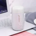 Detailansicht der weißen Mini-Thermotasse mit goldenem Sternenhimmelmuster auf dem Tisch. - 200ml / Weiß
