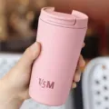 Nahaufnahme einer Hand, die einen tragbaren rosa 12-Unzen-Edelstahl-Kaffeebecher hält - 12oz / Rosa
