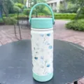 Gourde isotherme en inox avec motif d'eucalyptus sur une table de jardin extérieure. - Taille 600ml / Vert (Eucalyptus)
