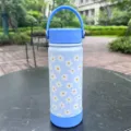 Vue détaillée de l'imprimé marguerites sur une gourde isotherme en acier inoxydable bleu clair. - Taille 600ml / Bleu (Marguerite)